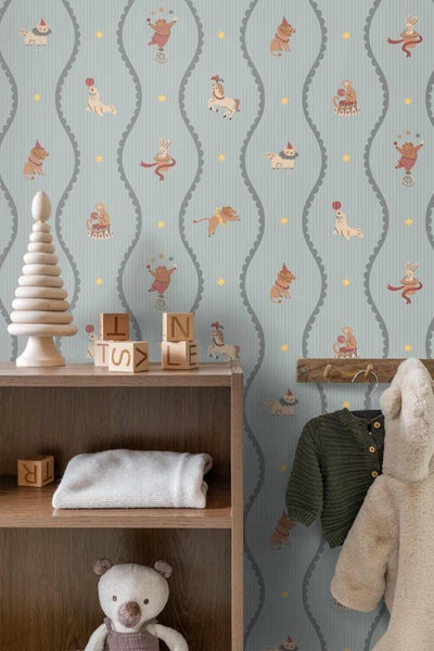 Kinderzimmer mit Zirkus-Tapete mit Tiermotiven und Wellenlinien, ein Holzregal mit Spielzeug und eine Garderobe mit Kinderkleidung.
