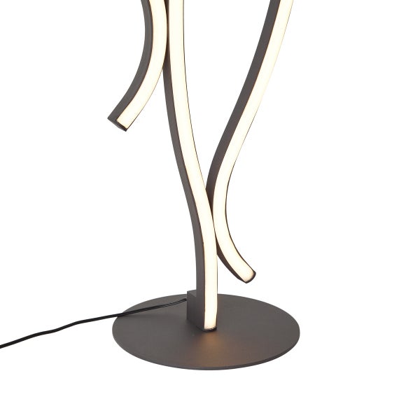 Moderne LED-Tischleuchte mit geschwungenen schwarzen Metallelementen und warmweißem Licht auf einem flachen runden Sockel.