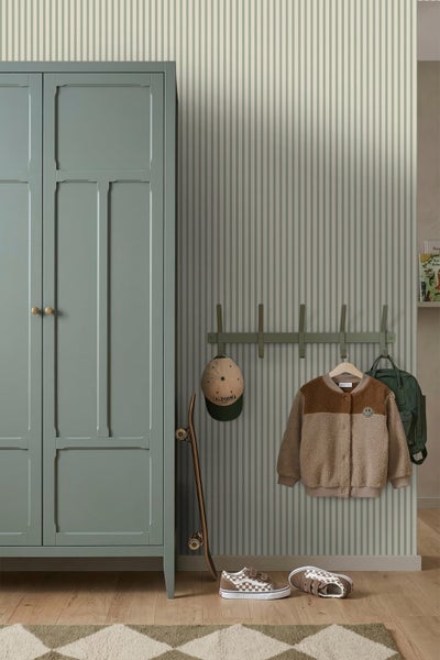 Vliestapete mit vertikalem Streifenmuster in einem Zimmer mit grünem Kleiderschrank, Wandgarderobe und Holzboden.