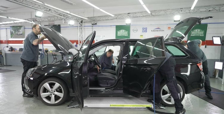 Ein Auto wird von mehreren Mechanikern in einer Werkstatt repariert.