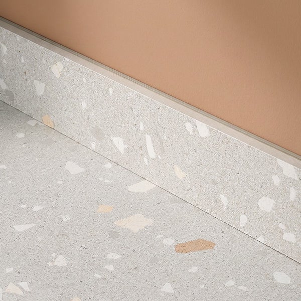 Sockelleiste mit Terrazzo Optik für Bodenfliesen mit einer Metallabschlussleiste an der Wand.