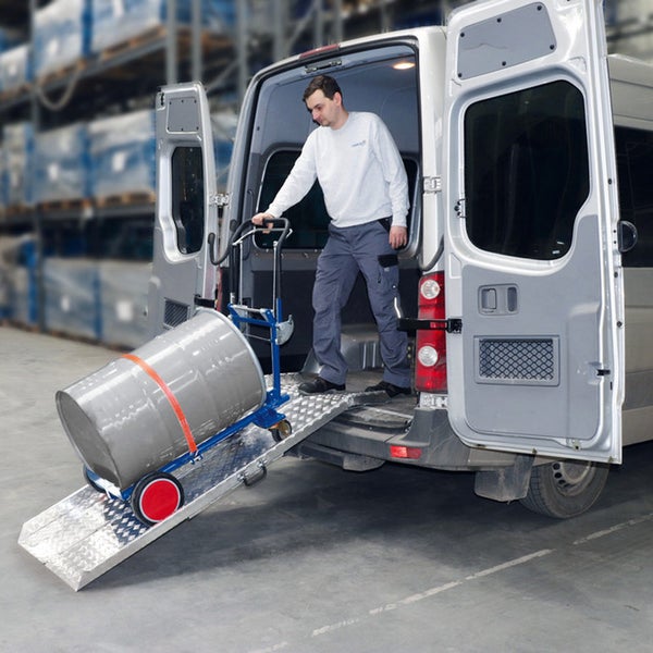 Ein Mann entlädt ein Fass mit einer Sackkarre über eine Aluminium-Auffahrrampe aus einem Transporter.