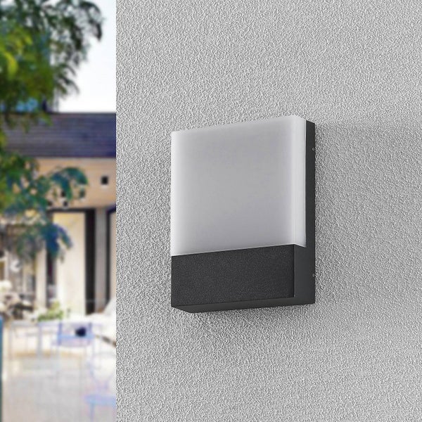 Quadratische Außenwandleuchte mit schwarzem Sockel und weißem Kunststoffdiffusor montiert an einer grauen Putzwand.