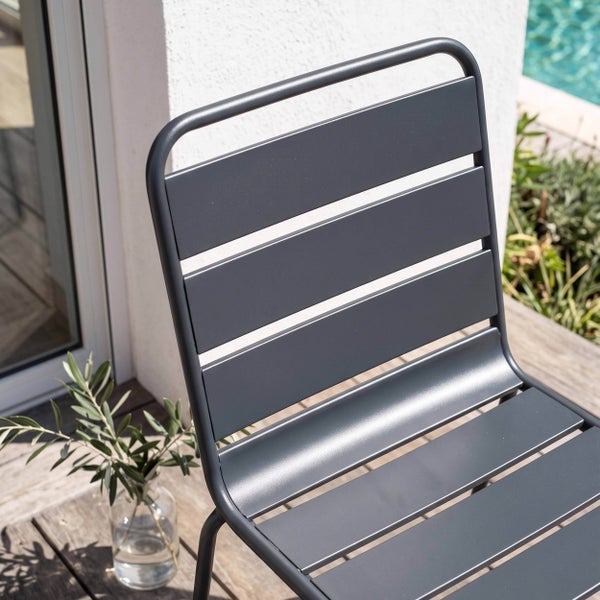Moderner Gartenstuhl aus Metall mit Lamellendesign auf einer Holzterrasse.