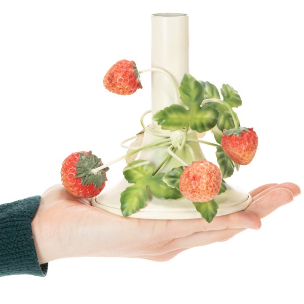 Cremefarbener Kerzenständer dekoriert mit künstlichen Erdbeeren und grünen Blättern, in einer Hand präsentiert.