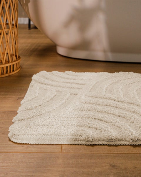Rechteckiger Badteppich in Beige mit Relief-Wellenmuster und Detailansicht der Oberflächenstruktur.