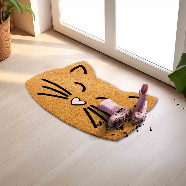 Fußmatte in Katzenform mit schmutzigen Gummistiefeln vor einer Tür