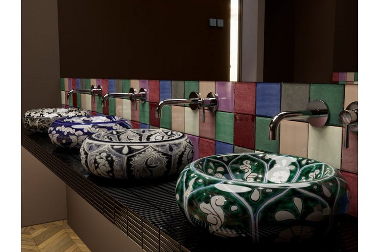 Mehrere Aufsatzwaschbecken mit verschiedenen Mustern und Armaturen auf einer Waschtischplatte.