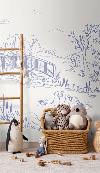 Kinderzimmer mit Landschaftstapete, Dekoleiter und Stofftieren in einem Korb
