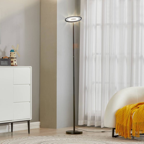Moderne LED-Stehleuchte mit ringförmigem Kopf in einem hellen Wohnzimmer neben einem weißen Sideboard und Sessel.