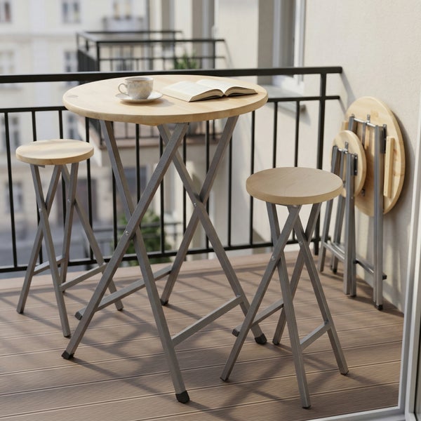 Klappbares Bartisch-Set bestehend aus einem runden Stehtisch und zwei Hockern mit hellen Holzplatten und grauen Metallgestellen auf einer Terrasse.