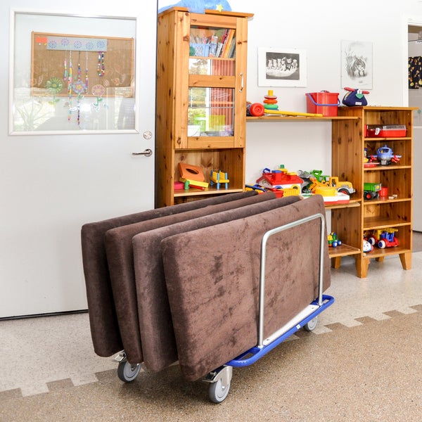 Klappmatratzen auf einem Rollwagen in einem Spielzimmer mit Holzregalen und Spielzeug