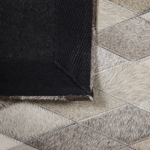 Teppich aus Fell-Patchwork mit Rautenmuster, Detailansicht der schwarzen Filz-Rückseite und der sichtbaren Nähte.