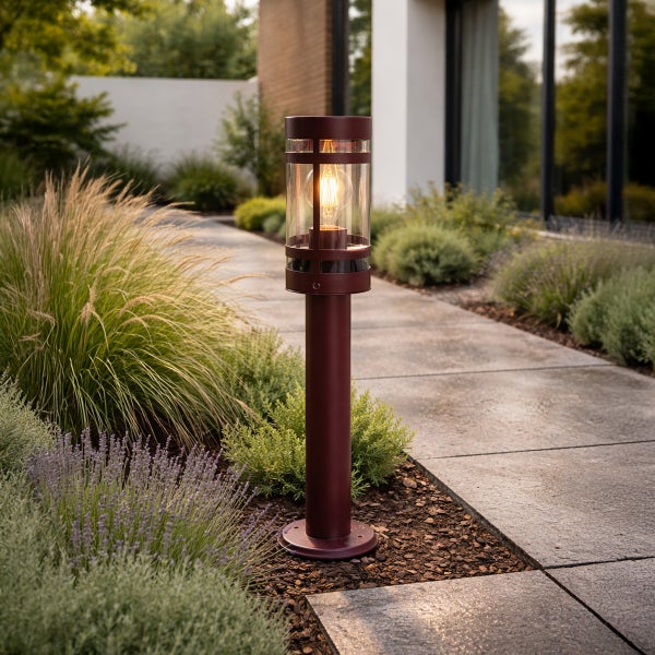 Dunkelrote Sockelleuchte aus Metall und Glas an einem Gartenweg zwischen Ziergräsern und Lavendel