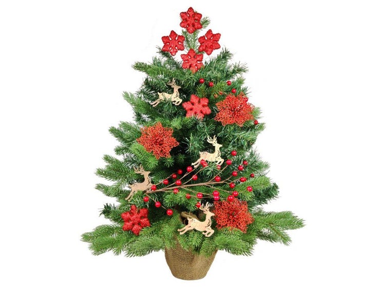 Künstlicher Weihnachtsbaum in einem Jutesack dekoriert mit Holzrentieren, Beeren und Blumen.