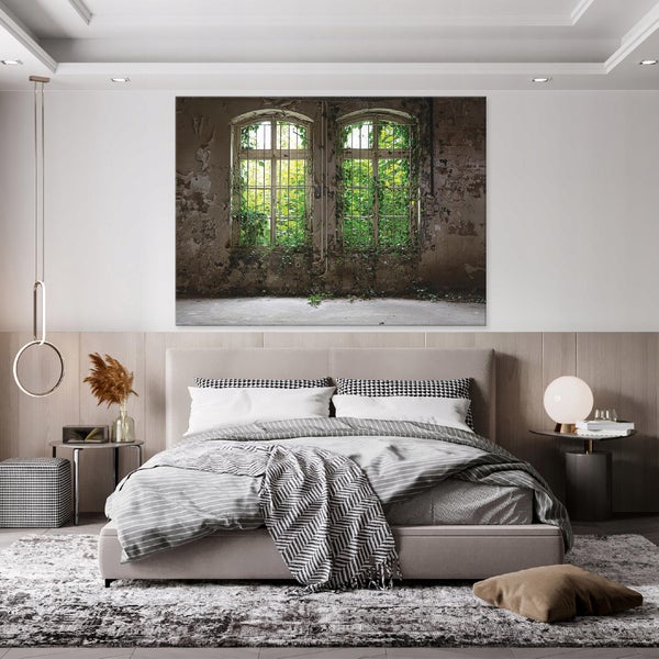 Modernes Schlafzimmer mit großem Wandbild über dem gepolsterten Bett, das bewachsene Fenster in einem verlassenen Raum zeigt.