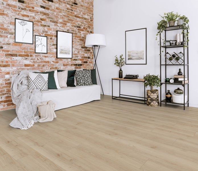 Wohnzimmer mit Laminatboden in Holzoptik vor einer Backsteinwand, dekoriert mit einem Sofa, Standleuchte und offenem Regal.