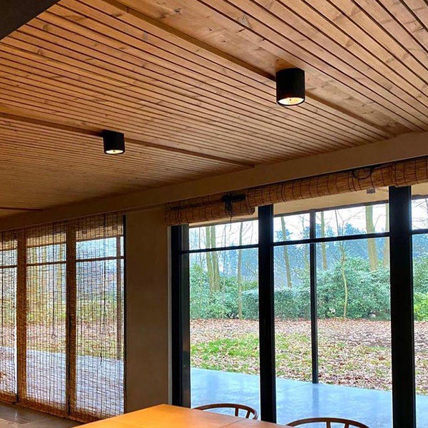 Zimmer mit Holzdecke und zwei Deckenleuchten.