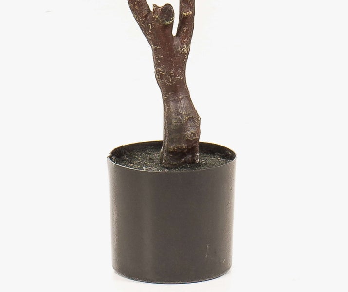 Nahaufnahme eines künstlichen Pflanzenstamms in einem schwarzen Kunststofftopf.