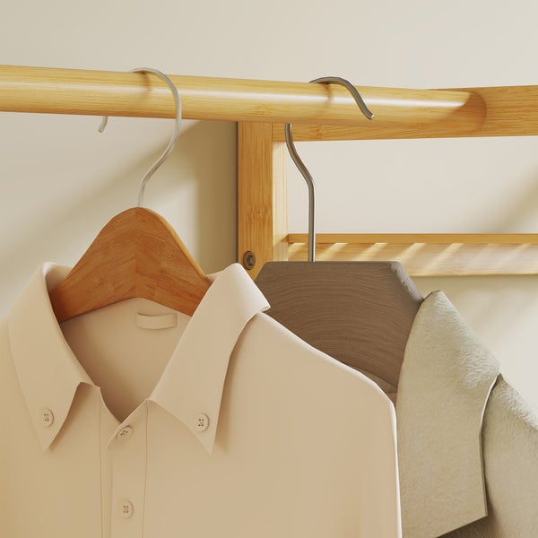 Nahaufnahme eines Kleiderständers aus Holz mit Kleiderbügeln. Ein helles Hemd hängt an einem Holzkleiderbügel an einer glatten Kleiderstange.