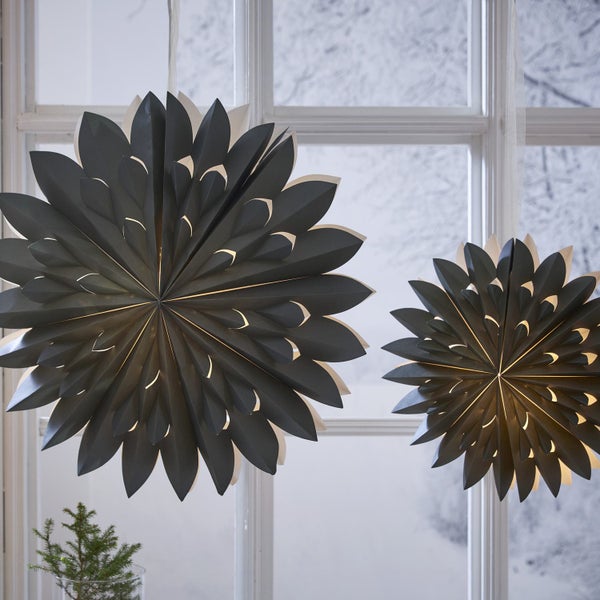 Zwei Papiersterne hängen vor einem Fenster und sorgen für dekorative Beleuchtung.