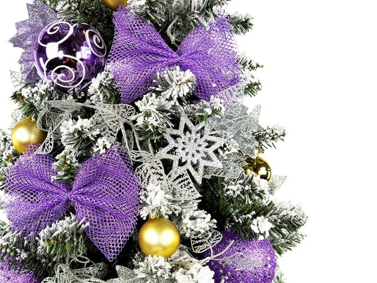 Künstlicher Weihnachtsbaum mit künstlicher Schneeoptik dekoriert mit lila Schleifen Weihnachtskugeln und Sternen für die festliche Dekoration