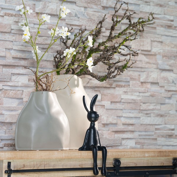 Dekorative Szene mit Blumen in Vasen und einer sitzenden Hasenfigur auf einem Regal.