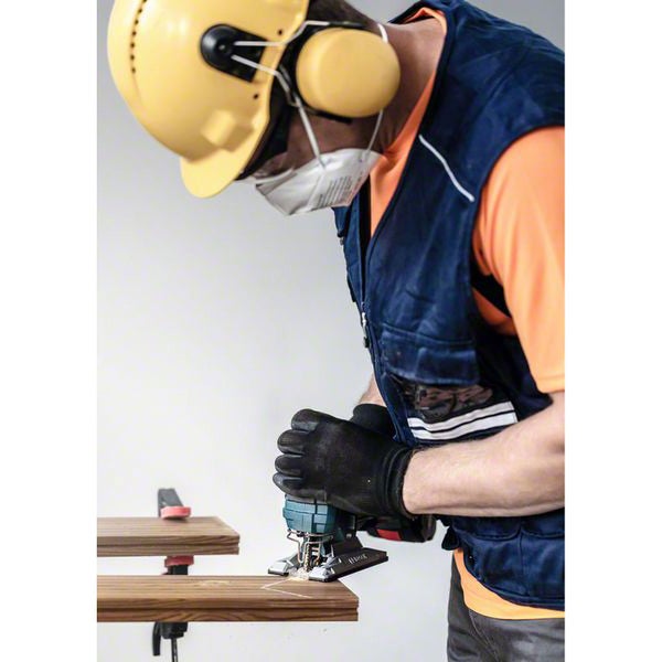 Mann sägt Holz mit Stichsäge, trägt dabei Schutzkleidung