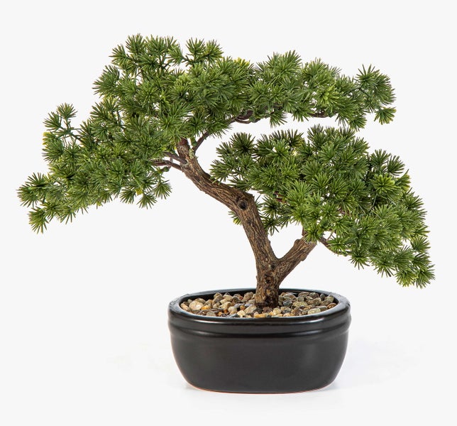 Künstlicher Bonsai in einer schwarzen Keramikschale mit dekorativen Kieselsteinen.