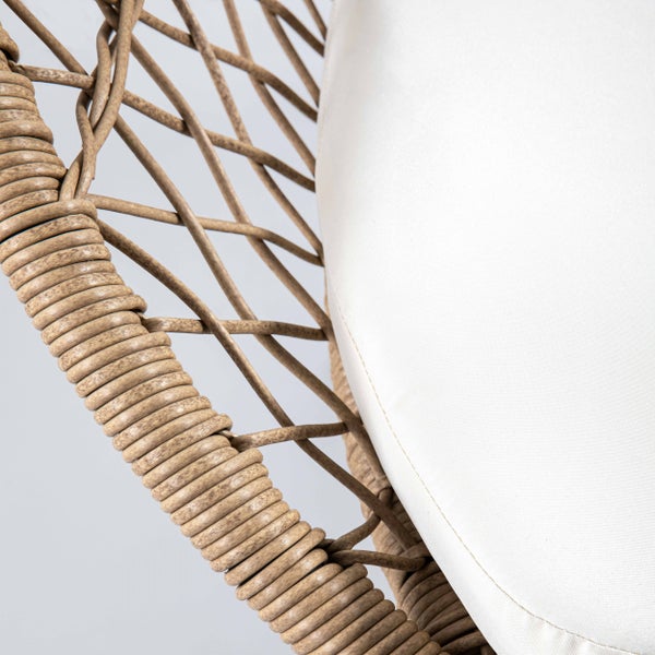 Detailaufnahme eines geflochtenen Sessels aus Rattan mit einem hellen Sitzkissen.