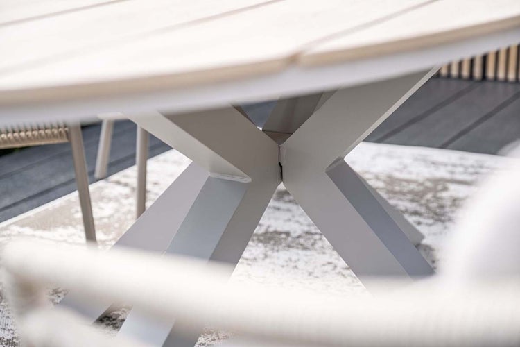 Detailansicht der X-förmigen Tischbeine aus Metall eines Gartentischs mit Holzlatten auf einer Terrasse.