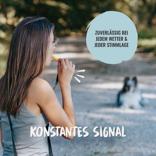 Eine Frau benutzt eine Hundepfeife im Freien, um ihrem Hund ein Signal zu geben.