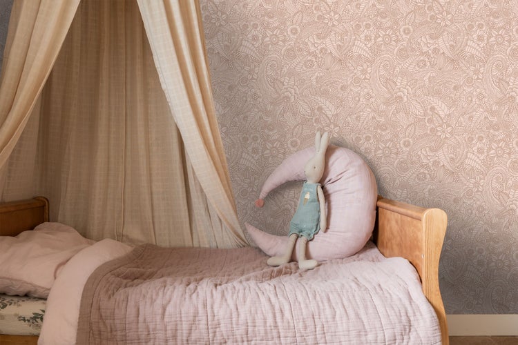 Vliestapete mit floralem Muster in einem hellen Kinderzimmer mit Holzbett, Betthimmel, Mondkissen und Stofftier.
