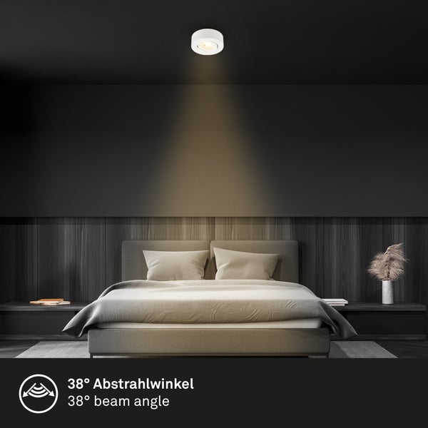 Moderner Deckenstrahler über einem Bett im Schlafzimmer mit Holzpaneelen an der Wand. Der Lichtstrahl hat einen 38 Grad Abstrahlwinkel.