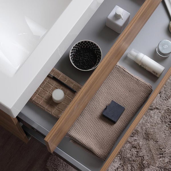 Moderner Waschtisch mit Holzfront und weißem Waschbecken an einer grauen Wand mit Spiegel, Stehlampe und dekorativen Wandbildern.