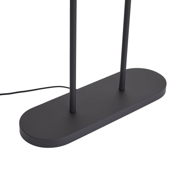 Ovaler Standfuß einer schwarzen Stehlampe mit zwei Stangen und Stromkabel.