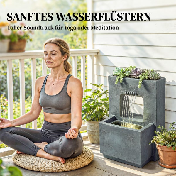 Eine Frau meditiert auf einer Terrasse neben einem modernen Gartenbrunnen in Steinoptik mit integrierter Pflanzschale für Sukkulenten.