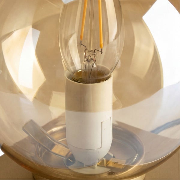 Nahaufnahme eines Filament-Leuchtmittels in einer Fassung, umgeben von einer transparenten Glaskugel auf einem Metallsockel.