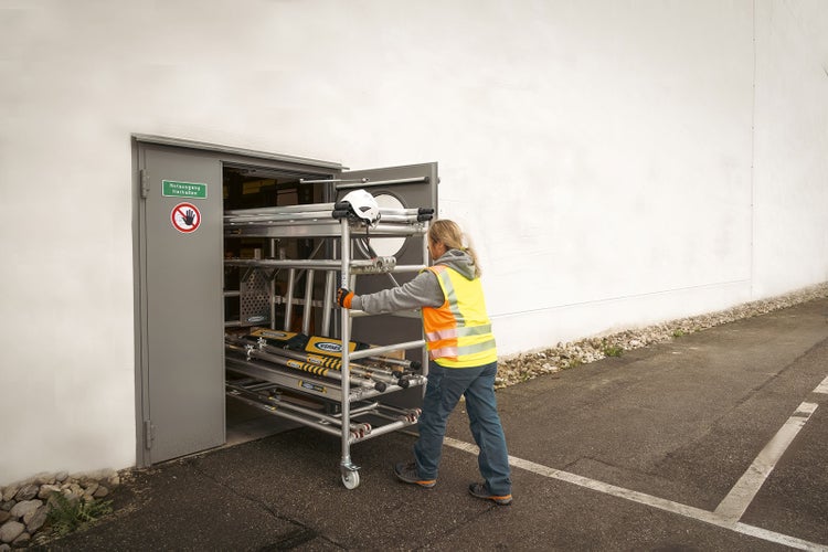 Frau schiebt Rollgerüst aus Lagerraum