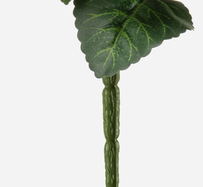 Detailaufnahme eines künstlichen Pflanzenstiels mit einem grünen Blatt mit gezacktem Rand und sichtbaren Blattadern.
