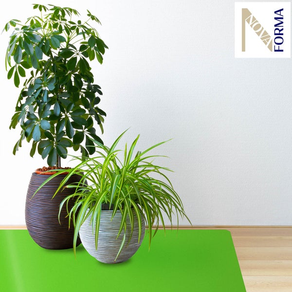 Eine Hand reinigt eine grüne Bodenschutzmatte auf einem Holzboden mit einem Tuch. Nova Forma Logo.