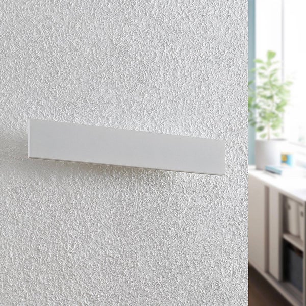 Moderne, flache Wandleuchte an einer strukturierten Wand in einem hellen Innenraum.