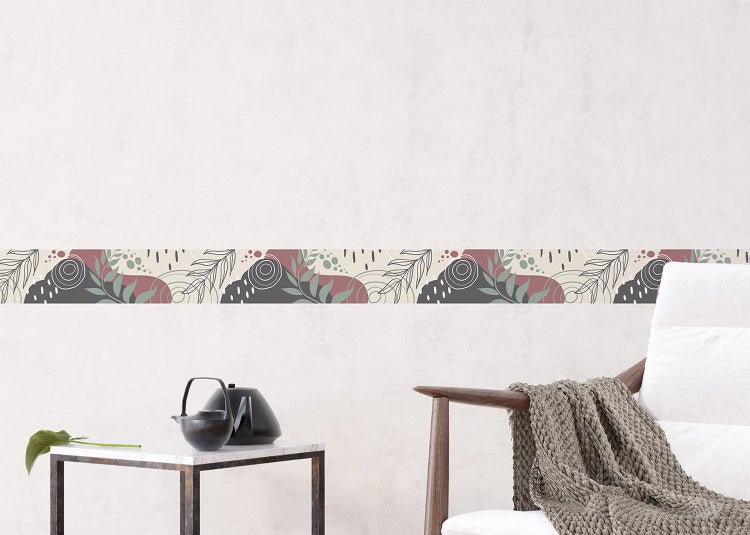 Vliestapete mit Fischgrätenmuster in verschiedenen Farben hinter einem weißen Sideboard mit Aufbewahrungsboxen und einem Deko-Kissen.