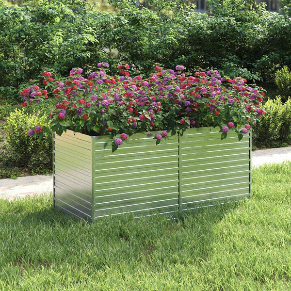 Rechteckiges Hochbeet aus gerilltem Metall, bepflanzt mit blühenden Blumen, auf einer Rasenfläche im Garten.