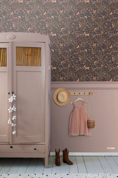 Vliestapete mit Waldtieren und Blumenmuster in einem Kinderzimmer hinter einem Gitterbett aus Holz.