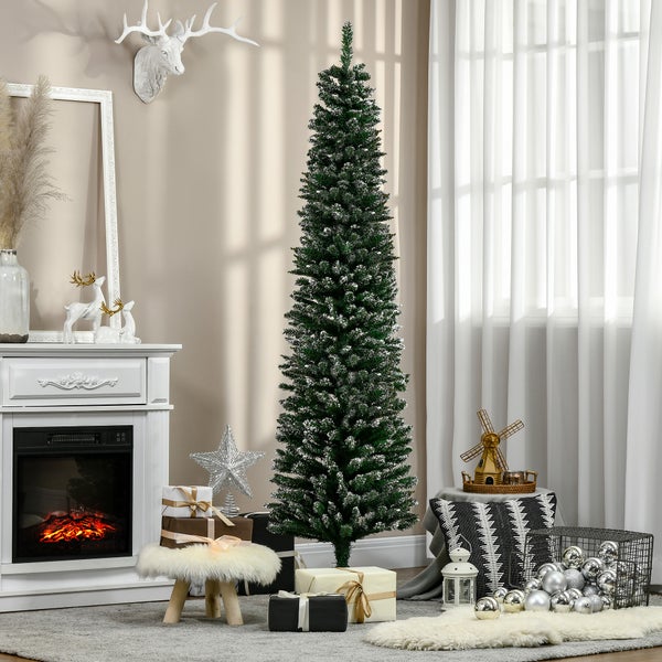 Schlanker künstlicher Weihnachtsbaum mit beschneiten Nadeln in festlichem Wohnzimmer mit weißem Kamin, Geschenken und Weihnachtsdekoration.