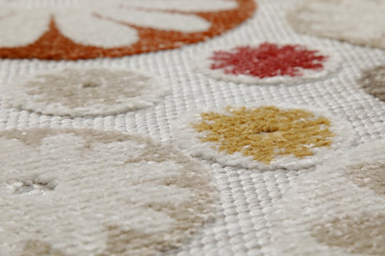 Nahaufnahme eines Teppichs mit runden, farbigen Blumenmotiven und unterschiedlichen Oberflächenstrukturen.