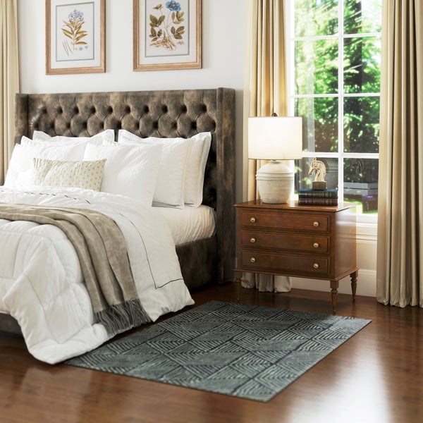 Helles, geräumiges Schlafzimmer mit dunkelgrauem Teppich mit Zickzackmuster auf dunklem Holzboden. Bett mit Polsterkopfteil und Nachttisch am Fenster.