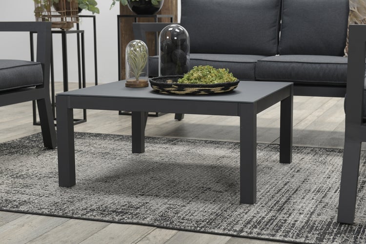 Moderner quadratischer Couchtisch in Dunkelgrau aus Metall, Teil einer organisierten Lounge-Garnitur mit Sofa und gemustertem Teppich.