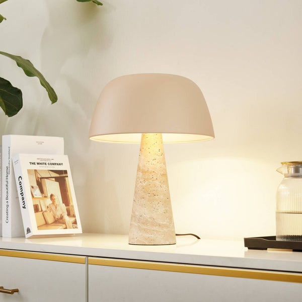 Moderne Tischleuchte mit kegelförmigem Steinfuß und runder Haube auf einem Sideboard neben Büchern in heller, organisierter Atmosphäre.